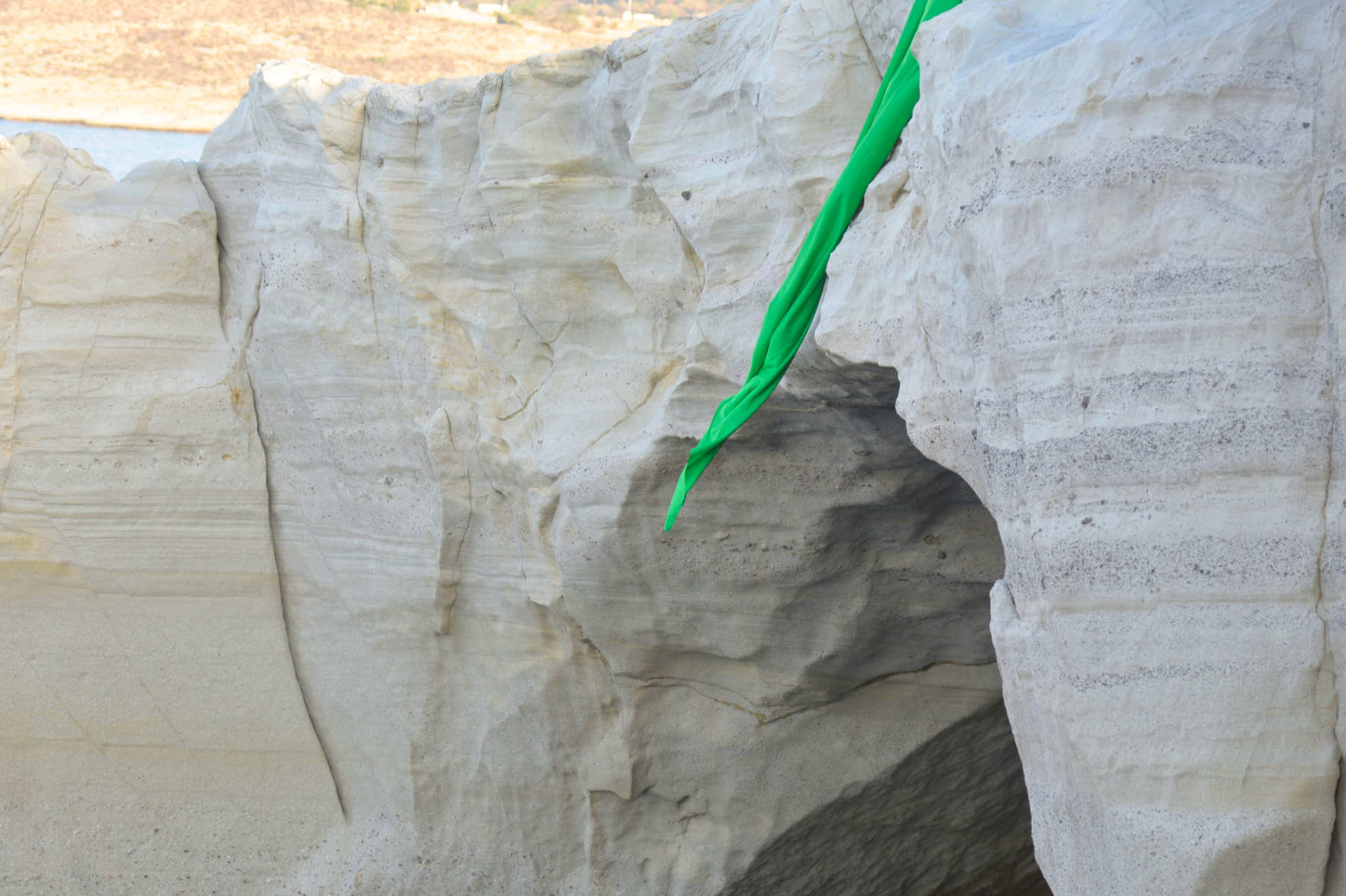 Green-screen fabric hanging into a gap in the white rock