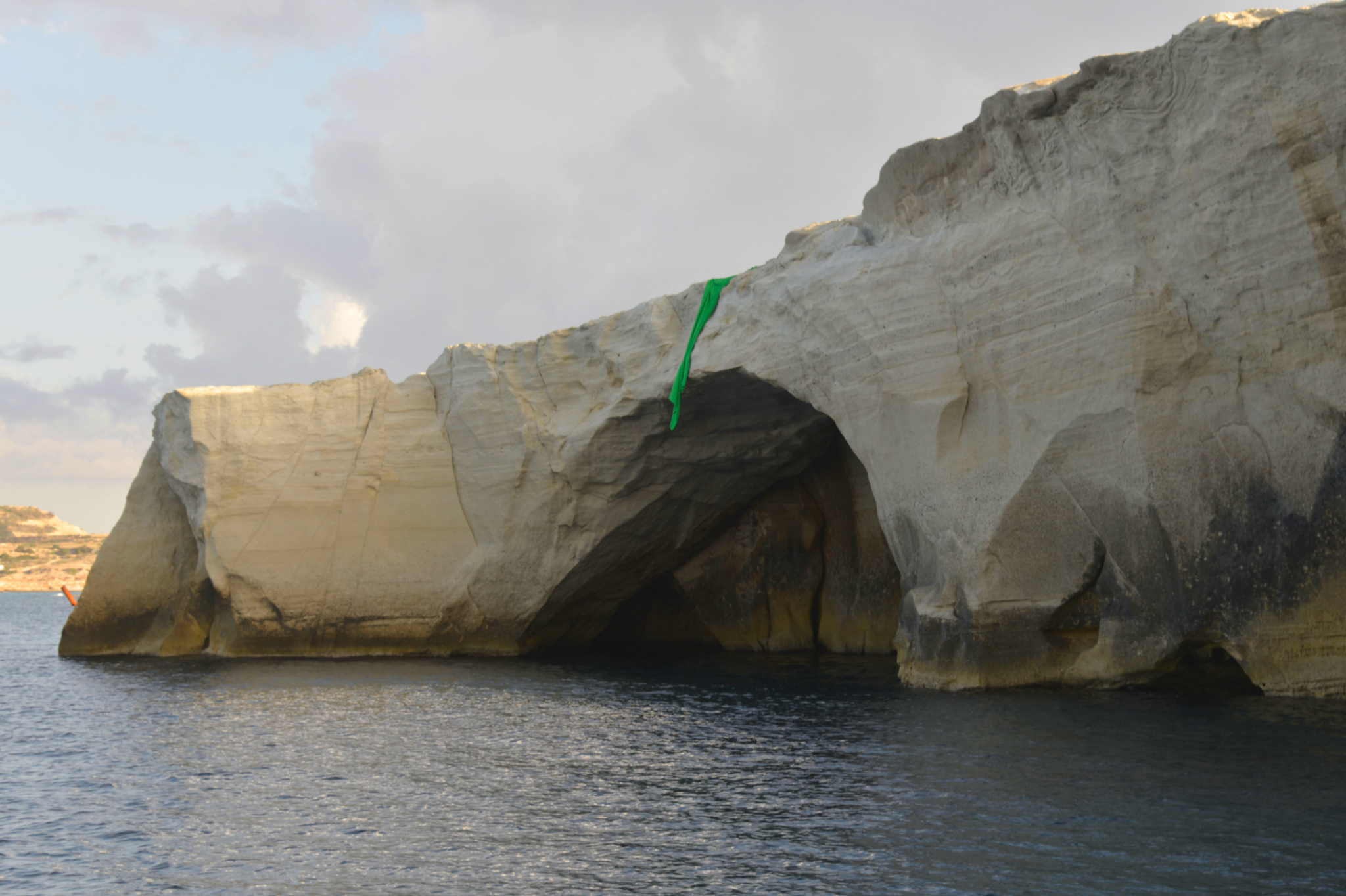 Green-screen fabric seen from a distance across the white cliffs of Sarakiniko