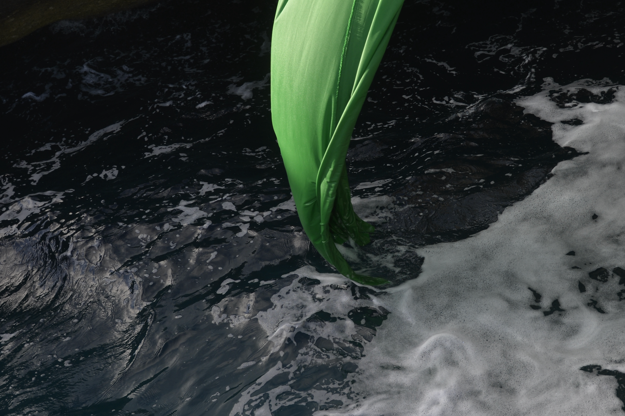 Green-screen fabric being washed among the rocks