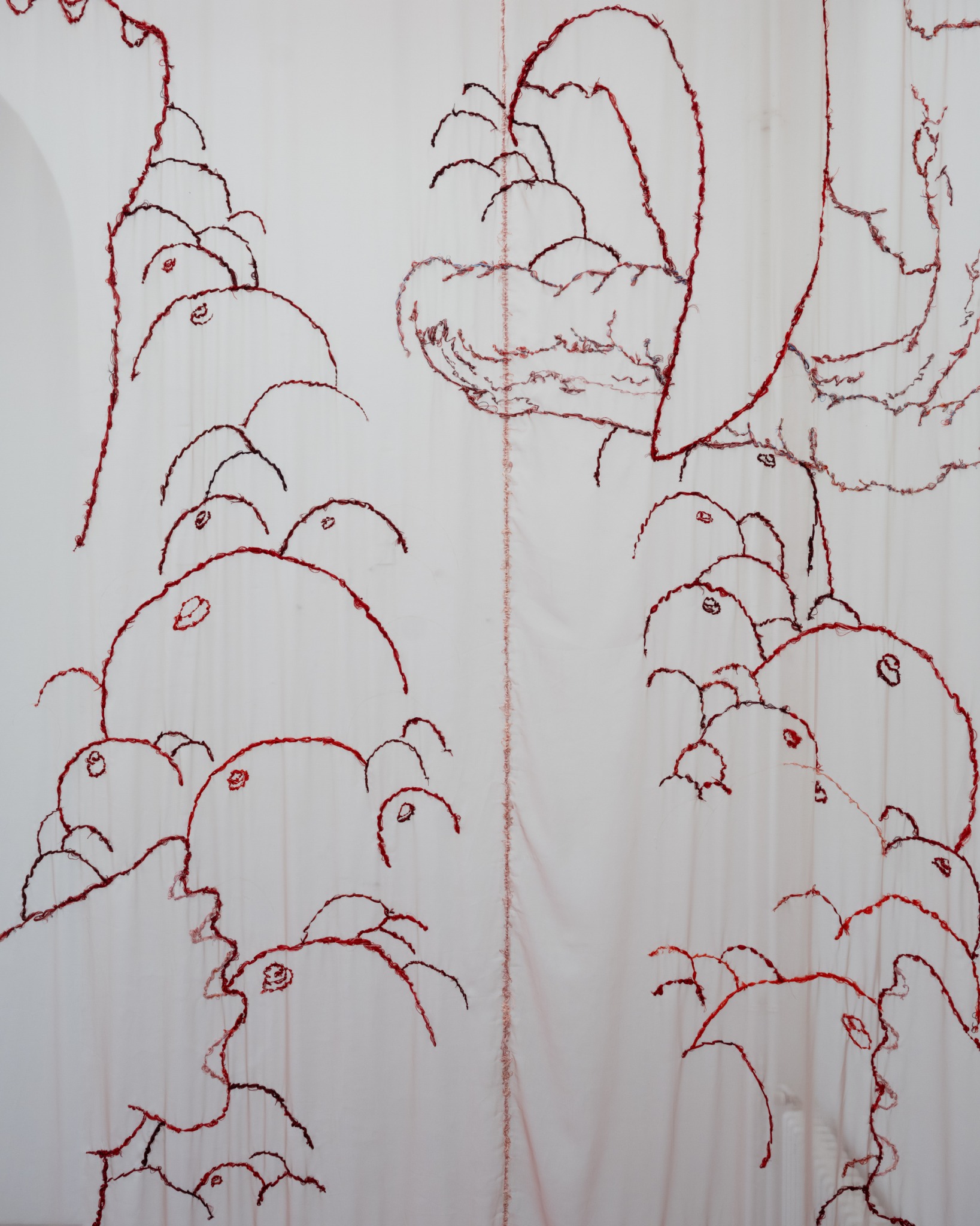 Close view of embryo forms embroidered in red silk